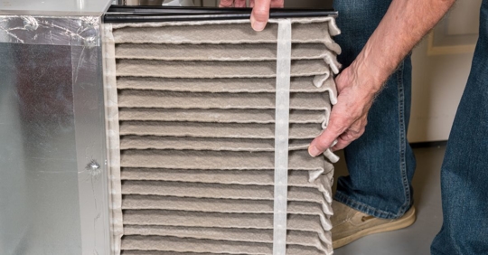 Man replaces a filter in a furnace