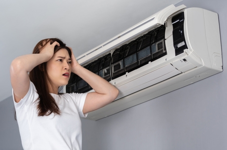 Stressed woman has problem with the air conditioner at home.