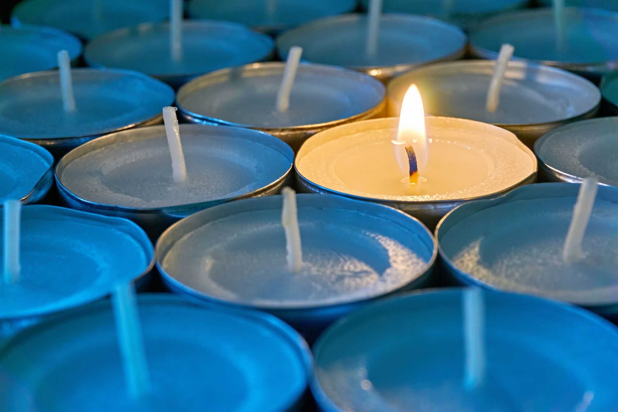 A bunch of candles with one lit